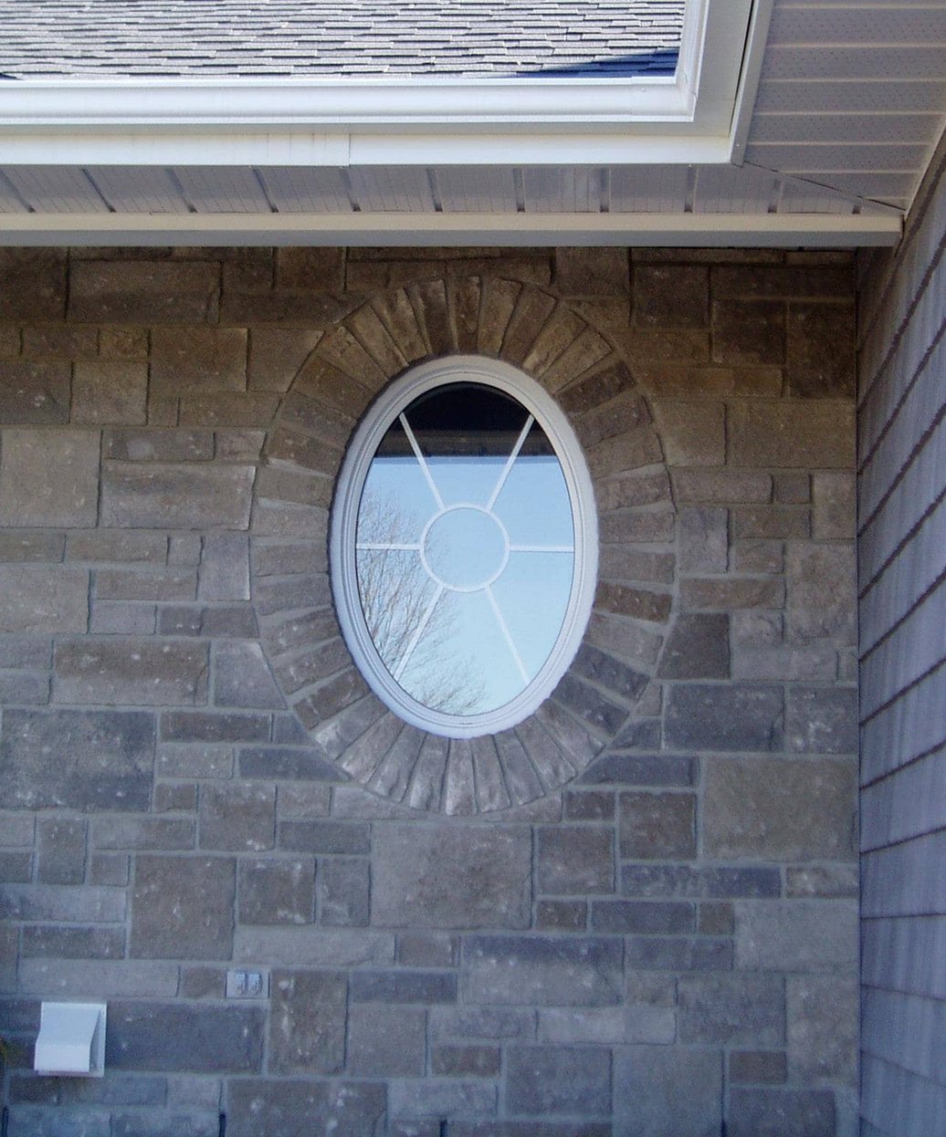 Stone veneer solider corse around a oval window in South Dundas